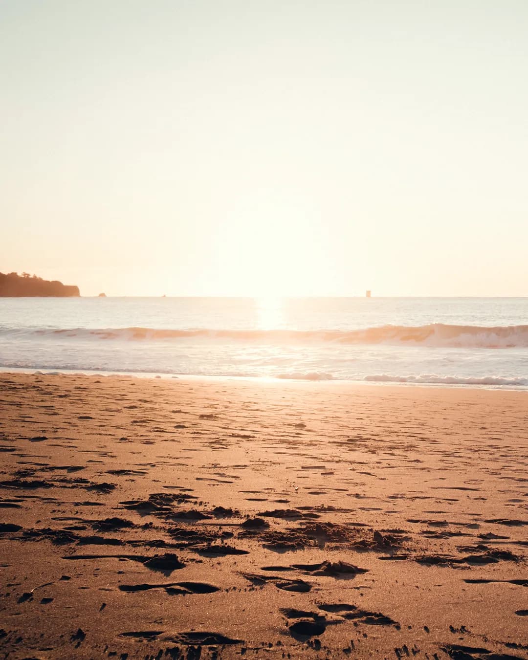 Person on a beach at golden hour, looking out at the calm ocean
