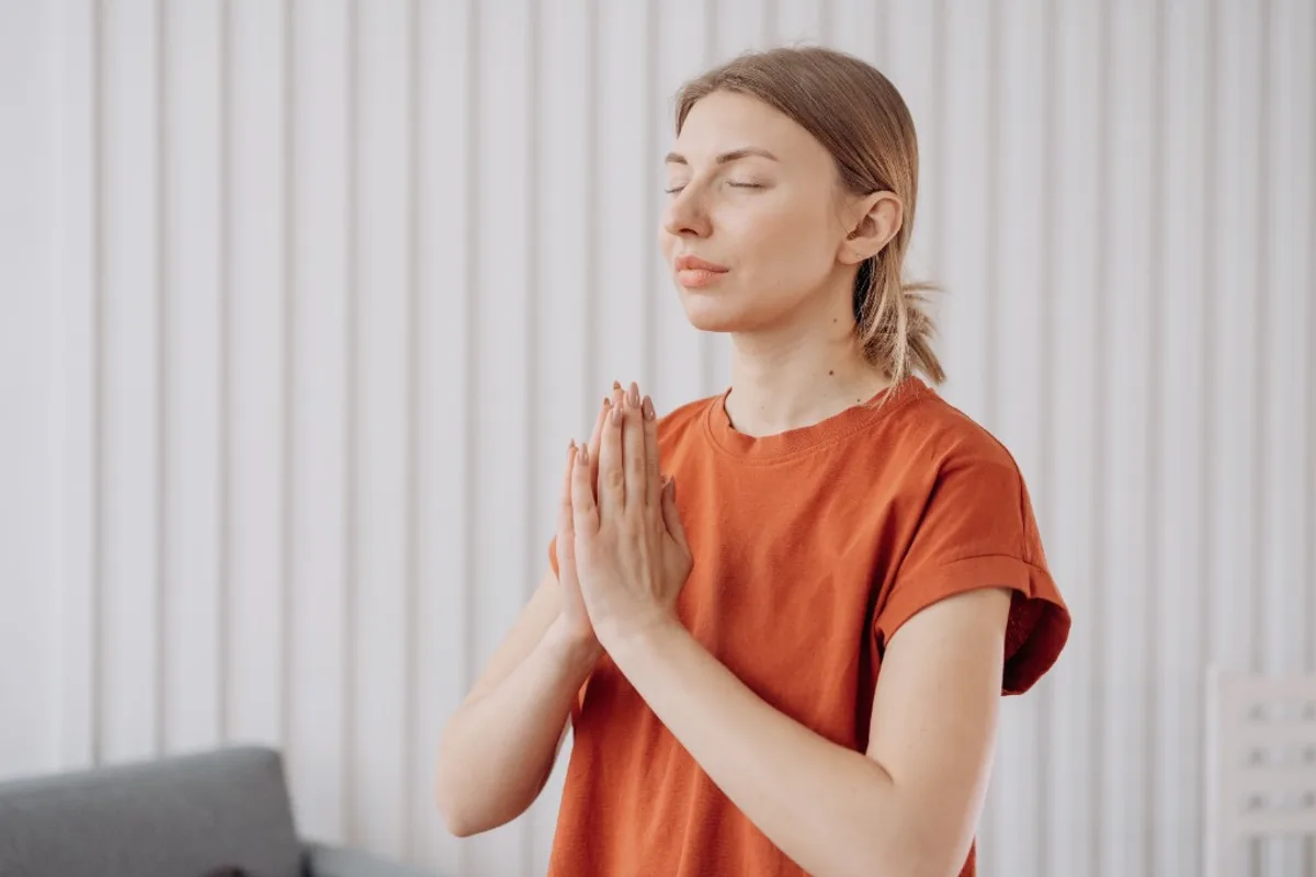 Person meditating with hands in prayer position