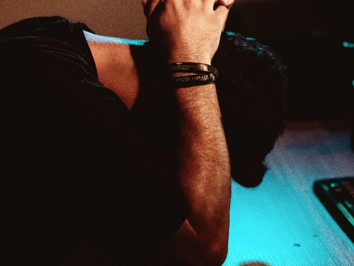 Person at a desk with head in hands in front of a computer