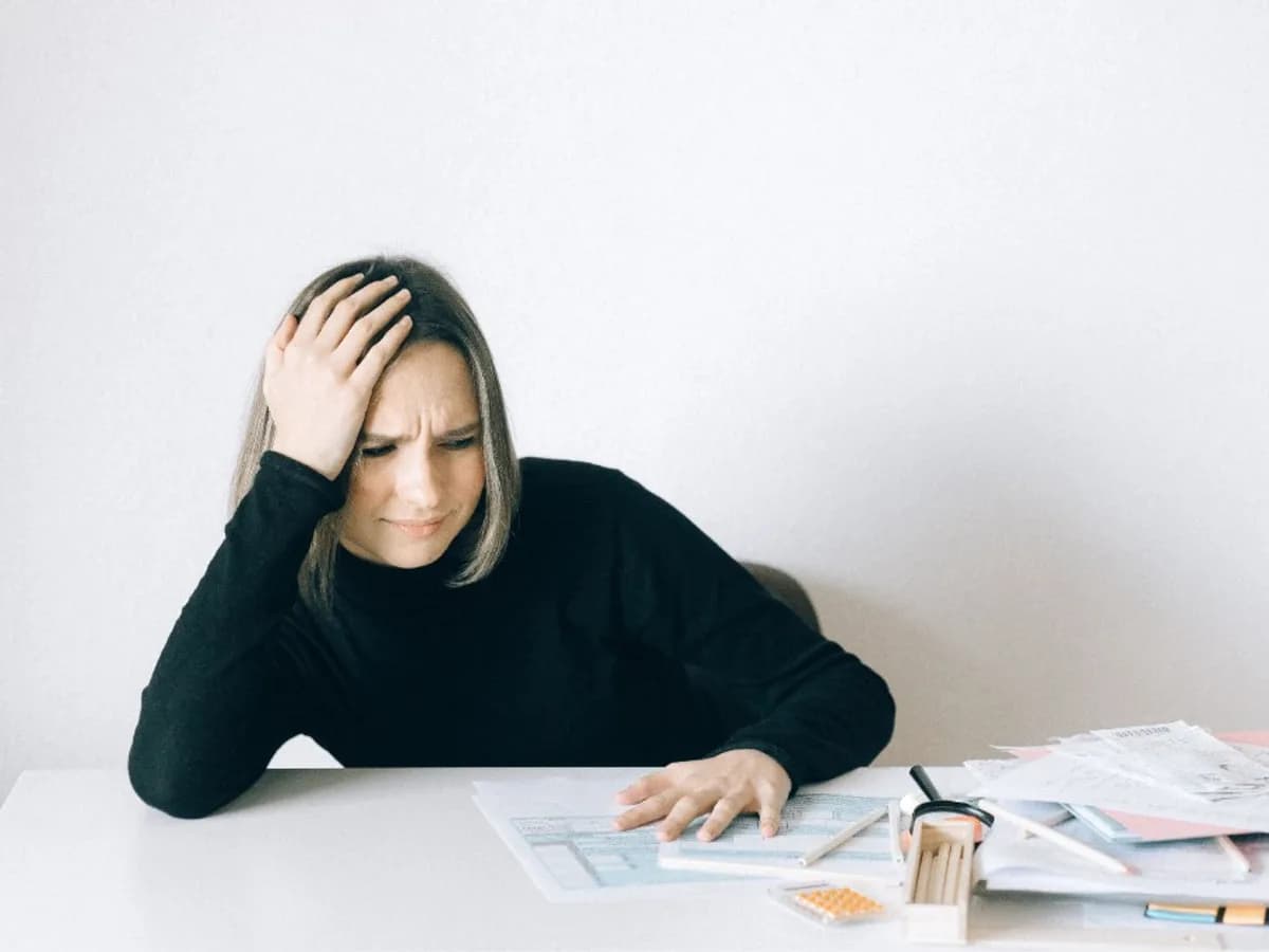 Woman stressed at a desk covered in paperwork