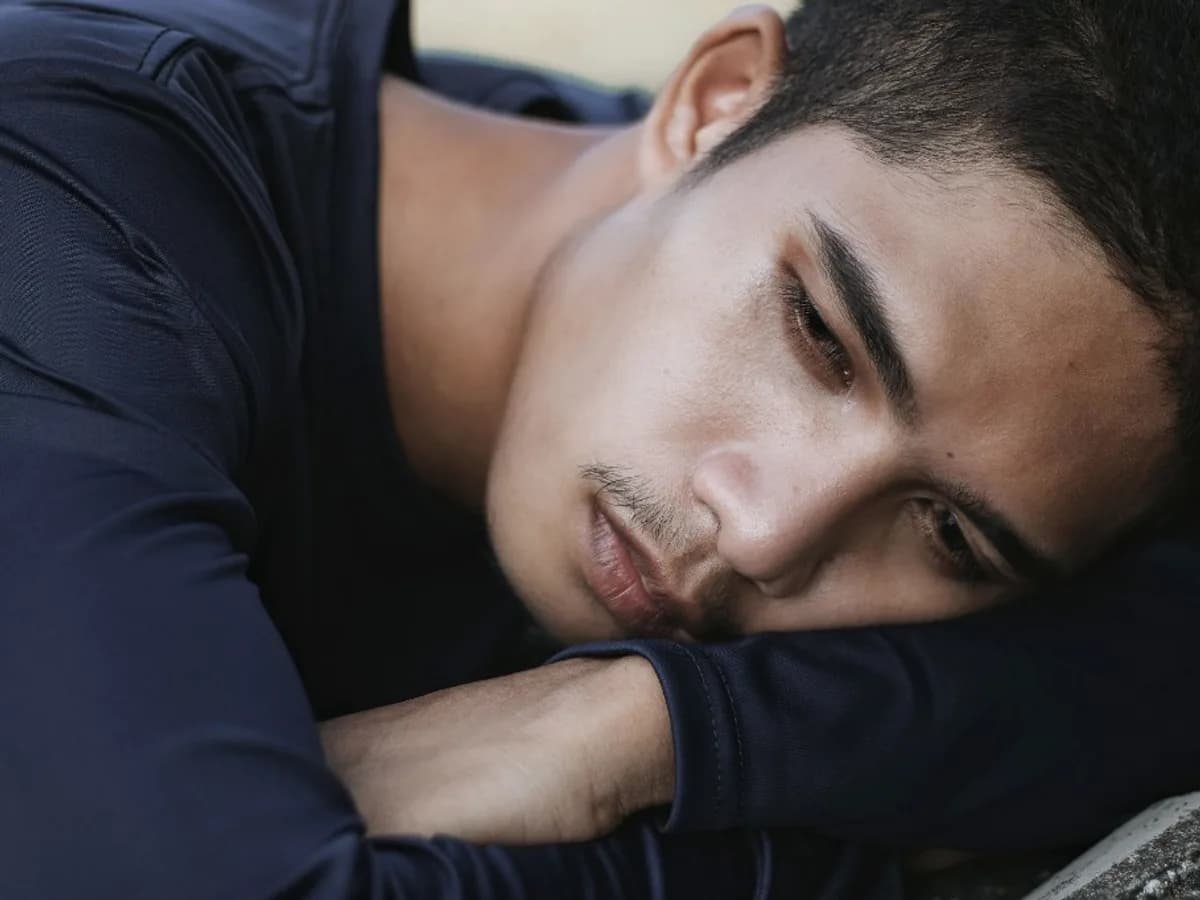 Young man resting his head on his arms, looking down
