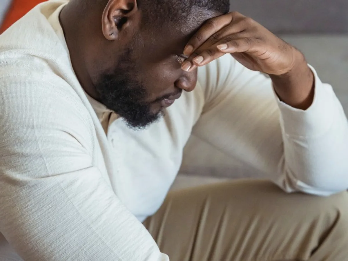 Man sitting on a couch with his hand on his forehead