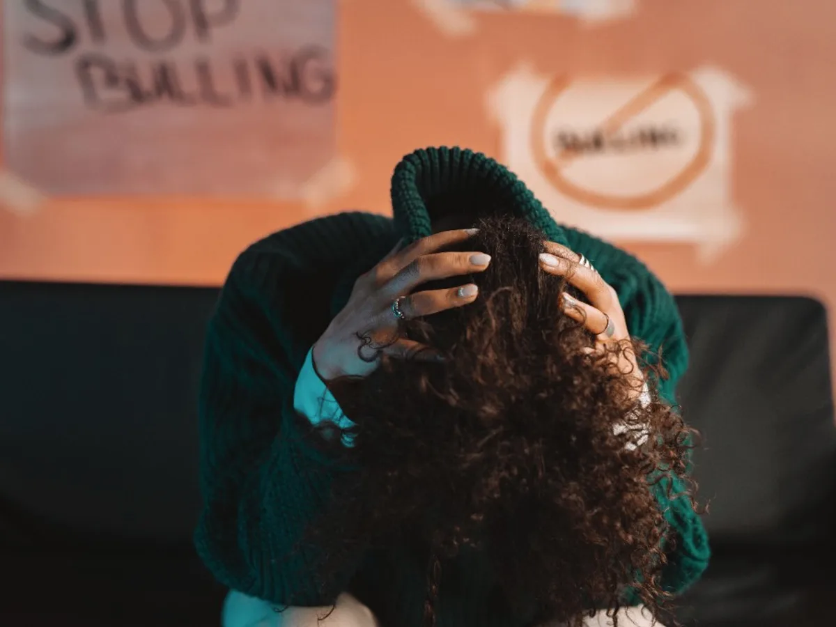 Person sitting with head in hands near anti-bullying posters