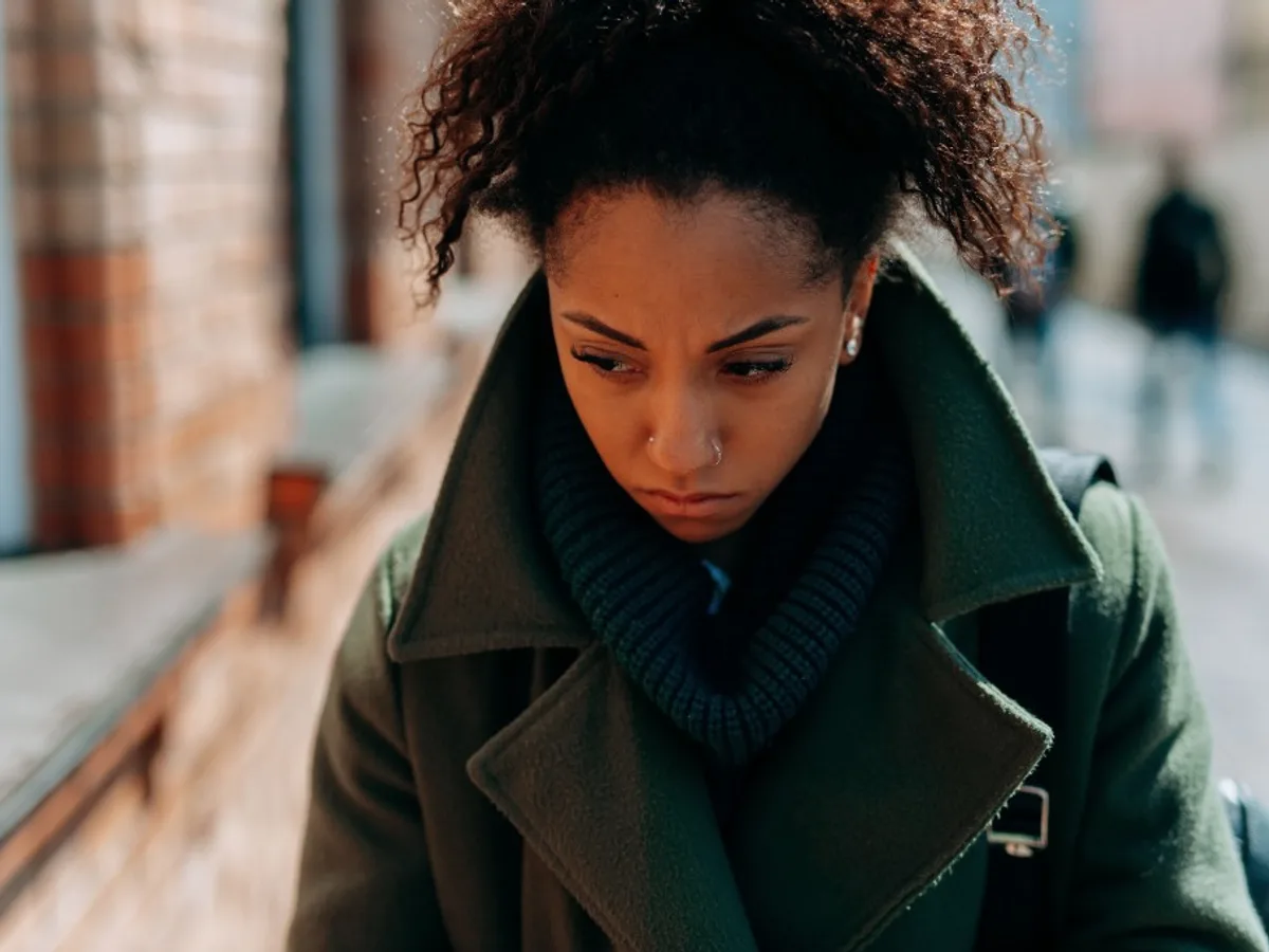Woman looking down with a serious, contemplative expression
