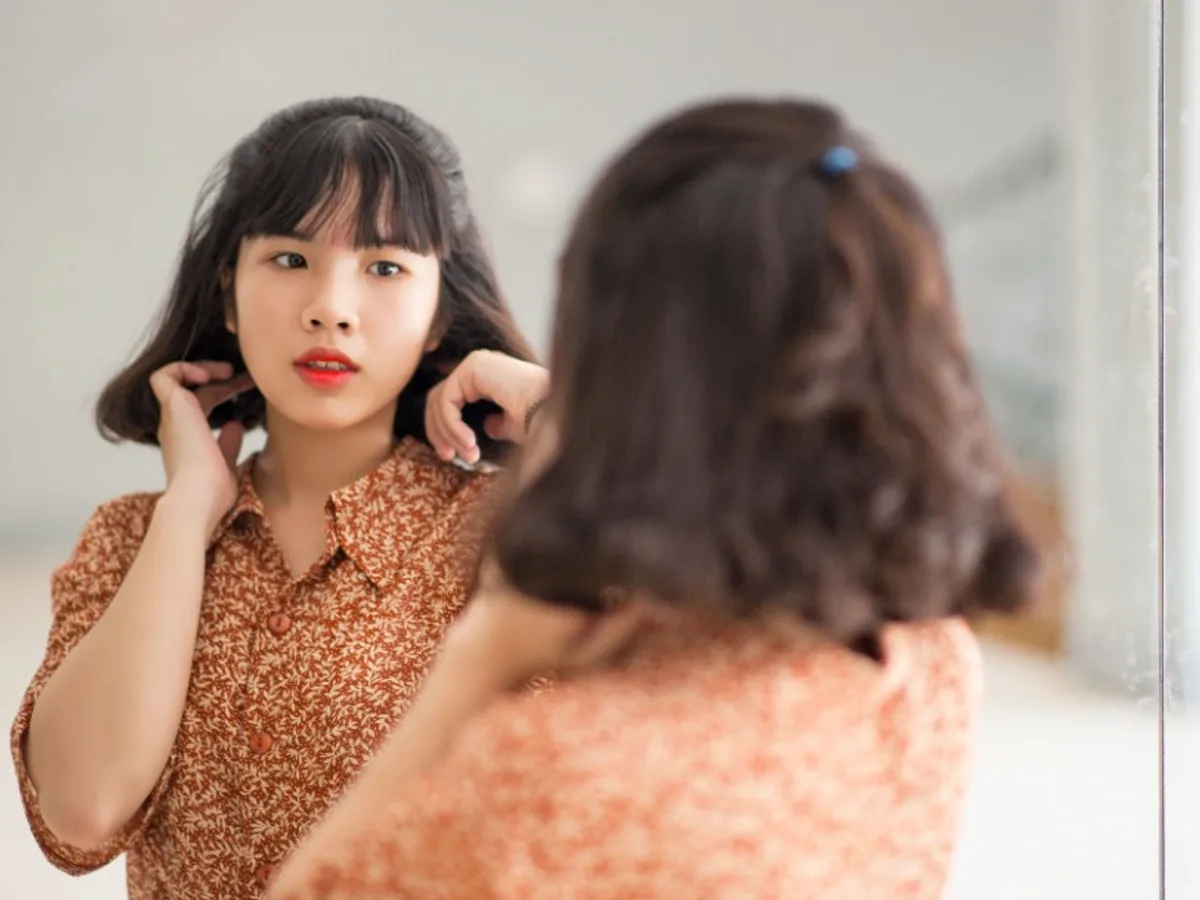 Woman looking at her reflection in a mirror